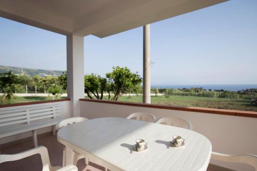 a white table and chairs in a room with a large window at Villa Alice in Capo Vaticano