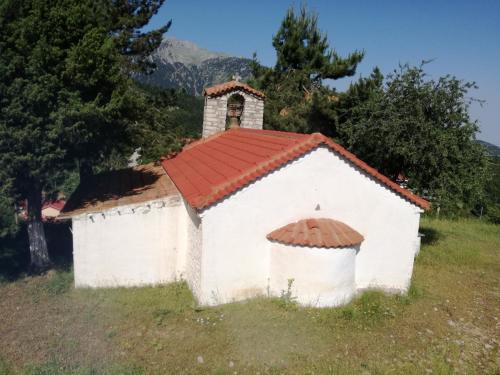 a small white chapel with a red roof on a hill at The Magic Mountain in Tsapournia