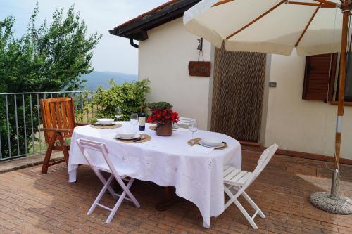 Biały stół z krzesłami i parasol na patio w obiekcie Il Borghetto di Carra w mieście Talla