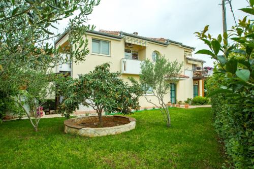 a house with a tree in a yard at Apartments Emma in Biograd na Moru