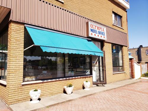 a restaurant with a blue awning and potted plants in front at Olympia Motel in Niagara Falls