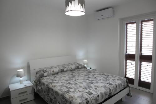 um quarto branco com uma cama e um lustre em Casa Felice em Ragusa