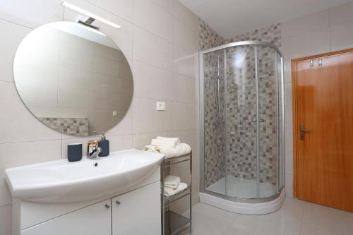 a white bathroom with a sink and a shower at House Pauline in Labin