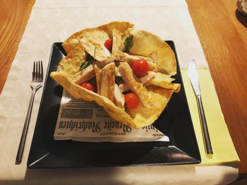 a black plate of food with a sandwich and chips at 16 Lakes Hotel in Grabovac