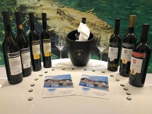 a table with wine bottles and wine glasses at 16 Lakes Hotel in Grabovac