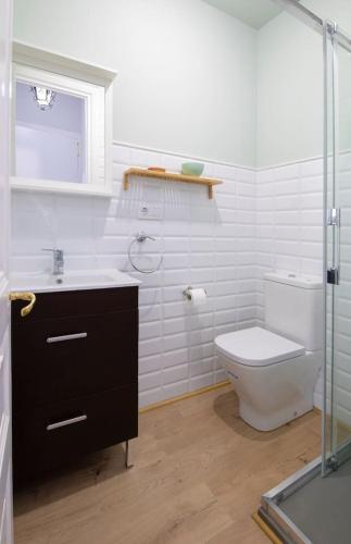 a white bathroom with a toilet and a sink at Apartamentos CASA CARRE 1893 in Santoña