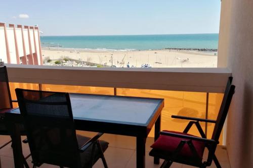 a table and chairs on a balcony with a view of the beach at Très bel appartement front de mer -4 personnes- in Palavas-les-Flots