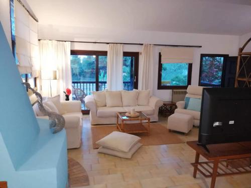 a living room with white couches and a tv at Seagull Villa Chalkidiki in Pefkohori