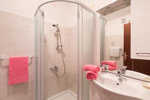 W łazience znajduje się umywalka, prysznic i różowe ręczniki. w obiekcie Apartment Calista w Rabacu