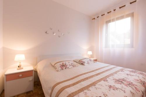 biała sypialnia z łóżkiem i oknem w obiekcie Apartment Calista w Rabacu