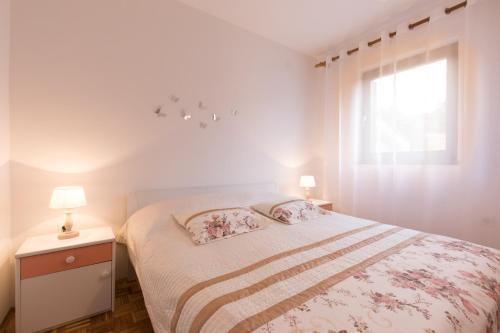 a white bedroom with a bed and a window at Apartment Calista in Rabac