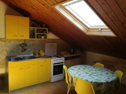 eine Küche mit einem Tisch, gelben Schränken und einem Fenster in der Unterkunft Guest House Vila Bak in Budva