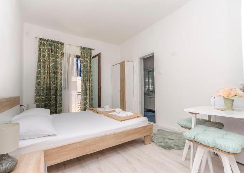 a white bedroom with a bed and a window at Apartments and Rooms Bepina in Vodice