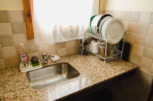 a kitchen counter with a sink and a window at Unquehue Apartamentos Dormis in Villa La Angostura