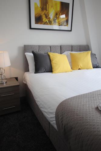 ein Schlafzimmer mit einem großen Bett mit gelben Kissen in der Unterkunft Halifax House, Studio Apartment 209 in Halifax