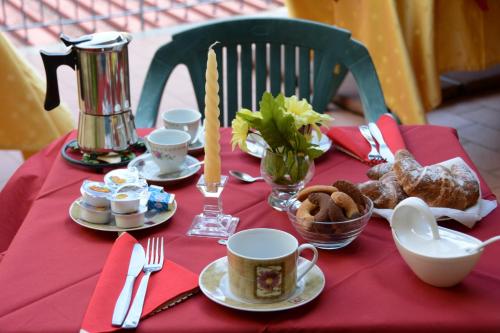 una mesa con un mantel rojo con tazas y platos de comida en B&B Casabella, en Riposto