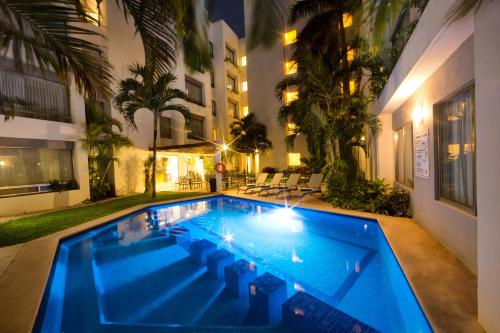 a swimming pool in front of a building at night at Ambiance Suites in Cancún