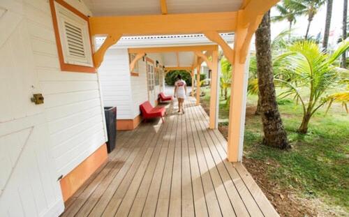 a woman walking on a wooden porch of a house at Studio Carayou in Les Trois-Îlets