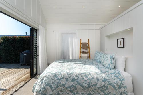 a bedroom with a bed and a balcony at Blackpool Boathouse - Stay Waiheke in Oneroa