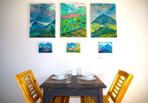 a table with two chairs and some paintings on the wall at Apartamentos Primavera in Jardin