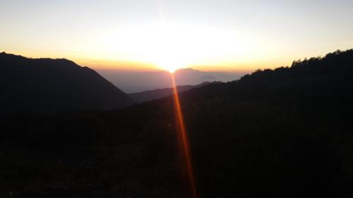 a sunset in the mountains with the sun setting at Homestay Anggun Bromo in Bromo