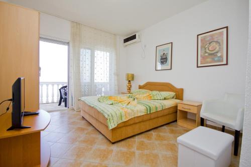 1 dormitorio con 1 cama, TV y escritorio en Apartments Dora, en Dobra Voda