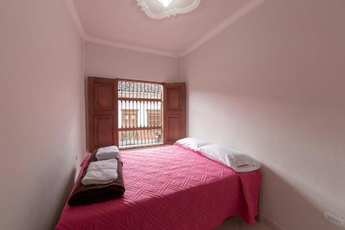a bedroom with a pink bed with a window at Apartamentos Primavera in Jardin