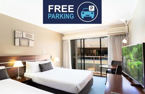 a hotel room with two beds and a sign that reads free parking at Riverside Hotel Southbank in Brisbane