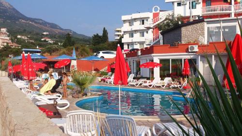 a pool with chairs and umbrellas next to a hotel at David apartments and rooms in Dobra Voda