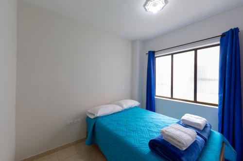 a bedroom with a blue bed and a window at Apartamentos Primavera in Jardin