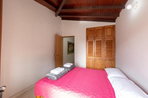 a bedroom with a pink bed with a wooden door at Apartamentos Primavera in Jardin
