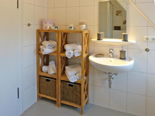 a bathroom with a sink and a shelf with towels at Ferienwohnung *Hüs Pelle* in Süddorf