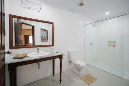 y baño con lavabo, aseo y espejo. en Bumas Hotel, en Sanur