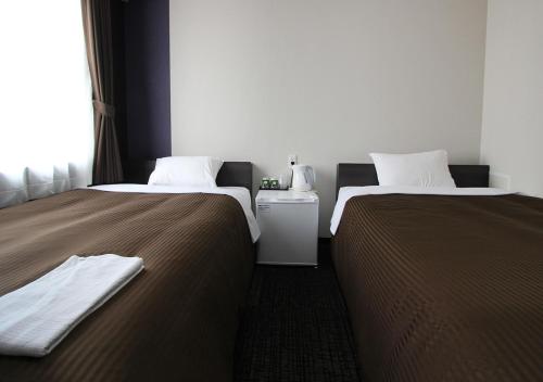 two beds sitting next to each other in a room at Hotel Trend Okazaki Ekimae in Okazaki