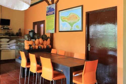 ein Esszimmer mit einem Holztisch und orangefarbenen Stühlen in der Unterkunft Downtown Monkey Forest Hostel in Ubud