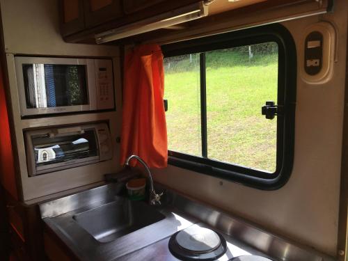 a kitchen with a sink and a window in a train at LA MESETA DE TOMINE CAMPER in Sesquilé