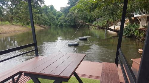 a view of a river from a porch with a table at Kaengkrachan River Hut in Kaeng Krachan