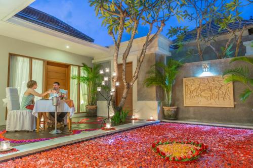 a man and woman sitting at a table in a room filled with red flowers at The Light Exclusive Villas and SPA - CHSE Certified in Seminyak