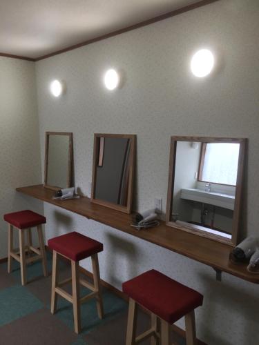 a bathroom with two mirrors and two red stools at Heart Hostel and Diner 女性専用Onlyfemale in Ise