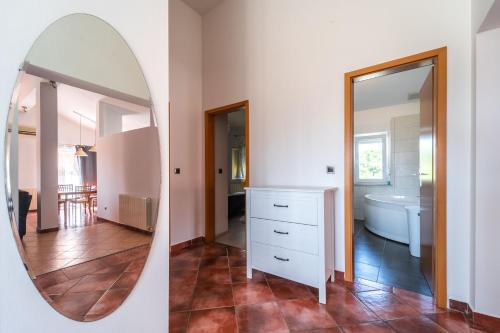a bathroom with a mirror and a white dresser at Apartman Debora sa privatnim bazenom in Pula