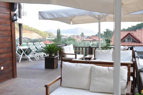 a patio with white chairs and an umbrella at Alya Hotel Göcek in Göcek