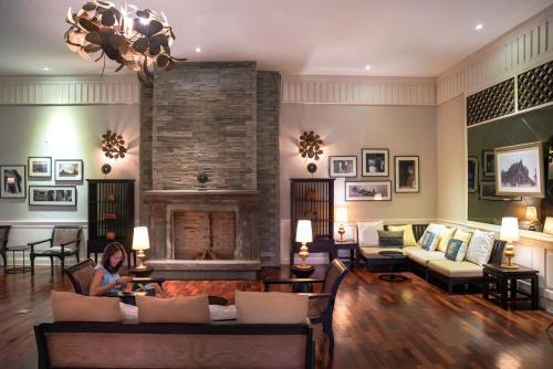 a woman sitting in a living room with a fireplace at Le Palais Juliana in Luang Prabang