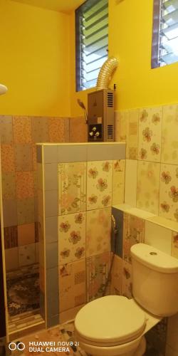 a bathroom with a toilet and a yellow wall at Bondoilampang in Ban Thung