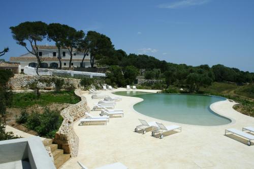 a swimming pool with lounge chairs and a resort at Hotel Rural Binigaus Vell in Es Migjorn Gran