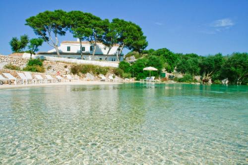 a view of a beach with chairs and a house at Hotel Rural Binigaus Vell in Es Migjorn Gran