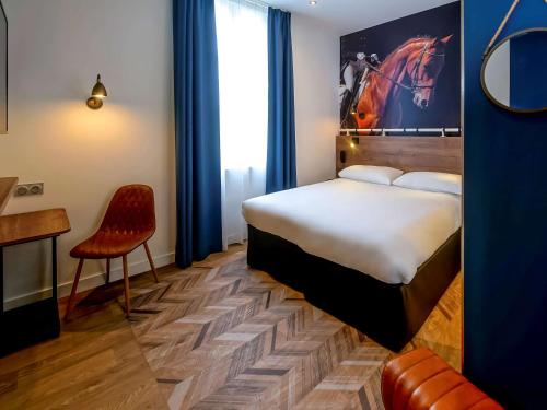 a hotel room with a bed and a chair at ibis Styles Saumur Gare Centre in Saumur