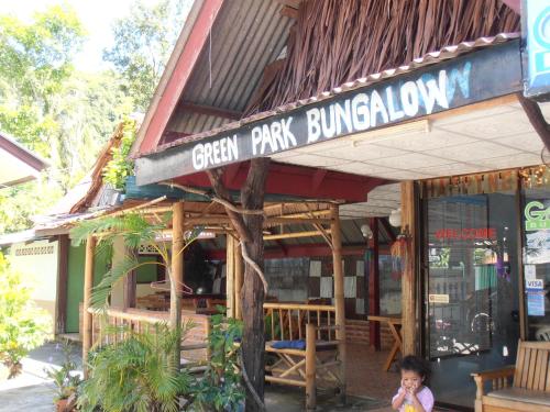 a small child standing in front of a green park building at Aonang Green Park Bungalow in Ao Nang Beach
