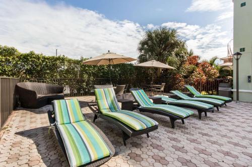 a row of lounge chairs and umbrellas on a patio at Quality Inn Boca Raton University Area in Boca Raton
