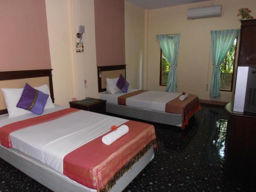 a hotel room with two beds and a television at Aonang Green Park Bungalow in Ao Nang Beach