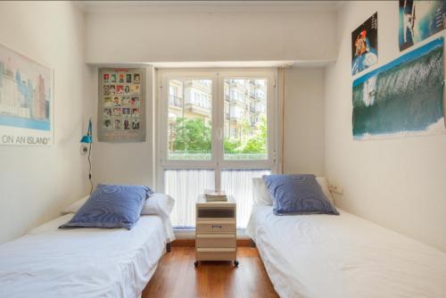 2 Betten in einem Zimmer mit Fenster in der Unterkunft Ondarreta Beach & Terrace in San Sebastián